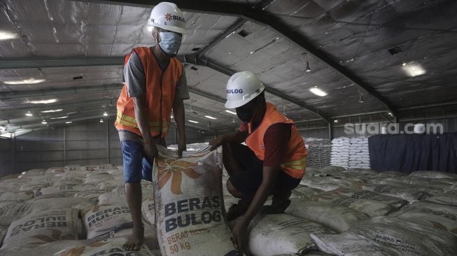 Pekerja menata karung berisi beras di Gudang Bulog Kanwil DKI dan Banten, Kelapa Gading, Jakarta, Kamis (18/3/2021). [Suara.com/Angga Budhiyanto]