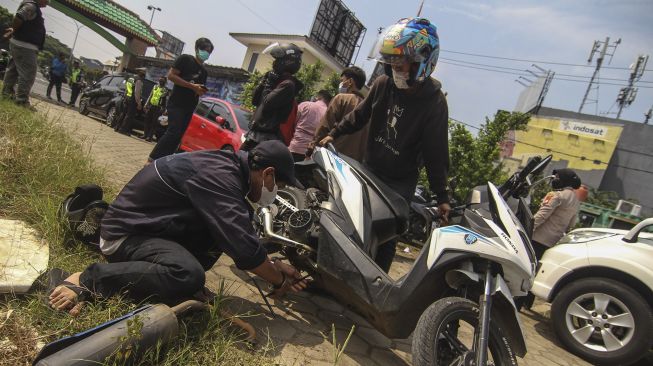 Pengendara mencopot knalpot bising usai terjaring razia yang digelar Satlantas Polres Metro Depok di Jalan Margonda, Depok, Jawa Barat, Jumat (19/3/2021).  ANTARA FOTO/Asprilla Dwi Adha