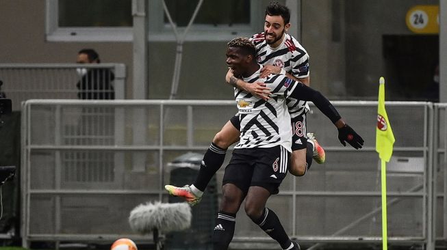 Gelandang Manchester United Paul Pogba merayakan golnya dengan gelandang Manchester United Bruno Fernandes setelah membuka skor selama pertandingan sepak bola leg kedua babak 16 besar Liga Eropa UEFA antara AC Milan melawan Manchester United di stadion San Siro, Milan, Italia,  Jumat (19/3/2021) dini hari WIB. Marco BERTORELLO / AFP
