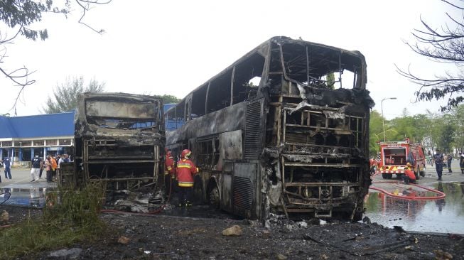 Petugas pemadam kebakaran menyemprotkan air untuk memadamkan sisa api saat kebakaran dua unit bus umum antar provinsi di Terminal Batoh, Banda Aceh, Aceh, Sabtu (20/3/2021). [ANTARA FOTO/Ampelsa]