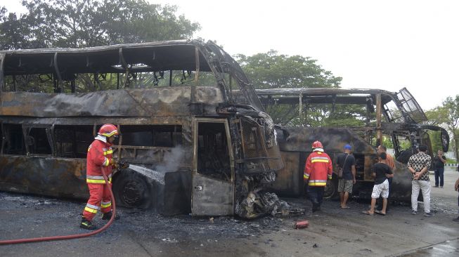 Petugas pemadam kebakaran menyemprotkan air untuk memadamkan sisa api saat kebakaran dua unit bus umum antar provinsi di Terminal Batoh, Banda Aceh, Aceh, Sabtu (20/3/2021). [ANTARA FOTO/Ampelsa]