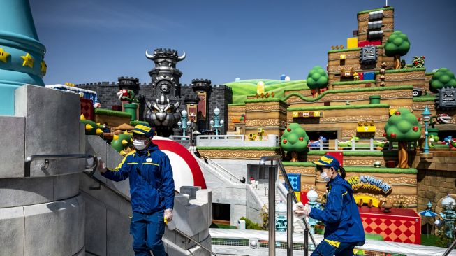 Petugas membersihkan fasilitas sebagai tindakan pencegahan terhadap COVID-19 di taman hiburan Super Nintendo World, Osaka, Jepang, pada (17/3/2021). [Philip FONG / AFP]