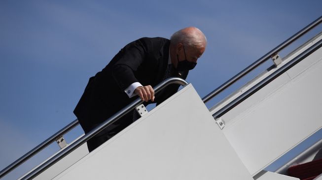 Presiden AS Joe Biden tersandung saat menaiki pesawat kepresidenan Air Force Ond di Pangkalan Gabungan Andrews, Maryland, 19 Maret 2021. ERIC BARADAT / AFP