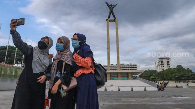 Warga berswafoto di Taman Lapangan Banteng, Jakarta Pusat, Minggu (21/3/2021). [Suara.com/Alfian Winanto]