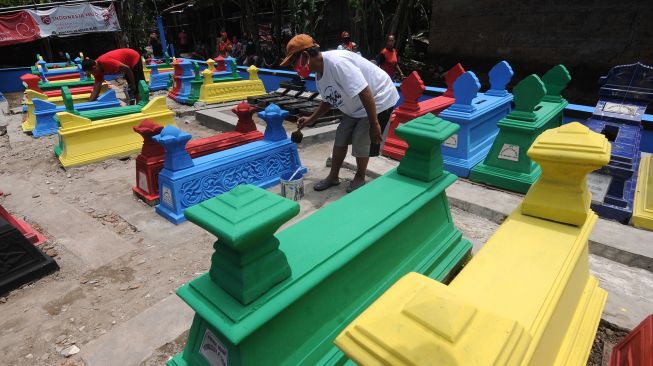 Seorang warga mengecat batu nisan di tempat pemakaman Gedhong Sasono Palereman, Jetis, Bakungan, Karangdowo, Klaten, Jawa Tengah, Senin (22/3/2021).  ANTARA FOTO/Aloysius Jarot Nugroho