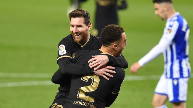 Megabintang Argentina Lionel Messi merayakan gol bersama rekan setimnya Sergino Dest saat Barcelona menang telak di kandang Real Sociedad dengan skor 1-6 di laga lanjutan Liga Spanyol, Senin (22/3/2021) dini hari WIB. (Foto: AFP)