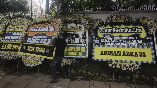 Pekerja menata karangan bunga tanda berduka cita atas meninggalnya Mantan Jaksa Agung Basrief Arief di rumah duka di kawasan Petogogan, Kebayoran Baru, Jakarta, Selasa (23/3/2021). [Suara.com/Angga Budhiyanto]