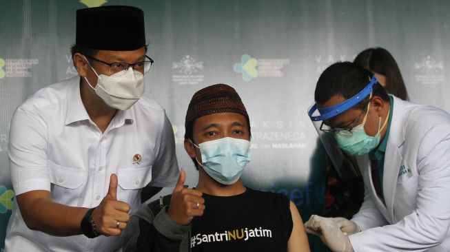 Menteri Kesehatan Budi Gunadi Sadikin (kiri) menyaksikan proses vaksinasi COVID-19 Astrazeneca kepada sejumlah kyai muda Nahdlatul Ulama (NU) di Kantor PWNU Jatim di Surabaya, Jawa Timur, Selasa (23/3/2021).  ANTARA FOTO/Moch Asim