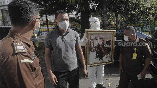 Salah satu anggota keluarga membawa foto Mantan Jaksa Agung Basrief Arief usai menyolatkan jenazahnya di rumah duka di kawasan Petogogan, Kebayoran Baru, Jakarta, Selasa (23/3/2021). [Suara.com/Angga Budhiyanto]