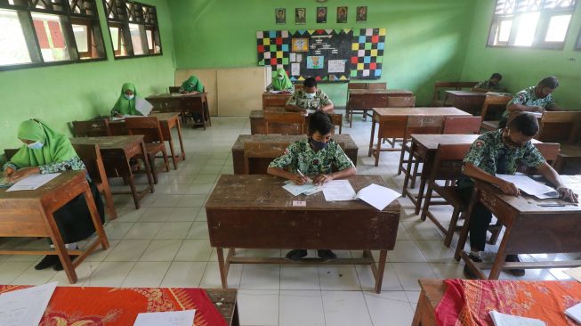 Pelajar mengerjakan soal ujian matematika di SMP Negeri 2 Tarokan, Kediri, Jawa Timur, Rabu (24/3/2021).  ANTARA FOTO/Prasetia Fauzani