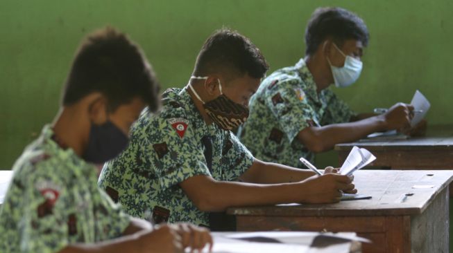 Pelajar mengerjakan soal ujian matematika di SMP Negeri 2 Tarokan, Kediri, Jawa Timur, Rabu (24/3/2021).  ANTARA FOTO/Prasetia Fauzani