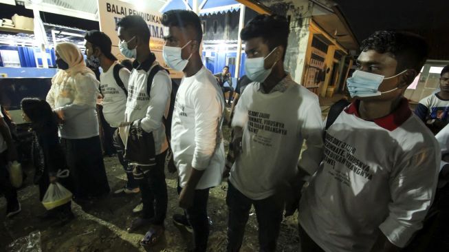 Pengungsi etnis Rohingya bersiap menuju bus saat akan diberangkatkan dari tempat penampungan Balai Latihan Kerja (BLK) Desa Meunasah Mee Kandang, Muara Dua, Lhokseumawe, Aceh, Kamis (25/2/2021) malam. [ANTARA FOTO/Rahmad]