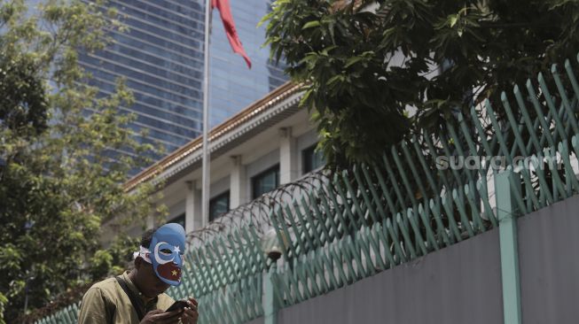 Seorang massa yang tergabung dalam Aliansi Mahasiswa Islam (AMI) beristirahat di sela-sela melakukan aksi unjuk rasa di depan Kedutaan Besar Republik Rakyat China, Kuningan, Jakarta, Kamis (25/3/2021). [Suara.com/Angga Budhiyanto]