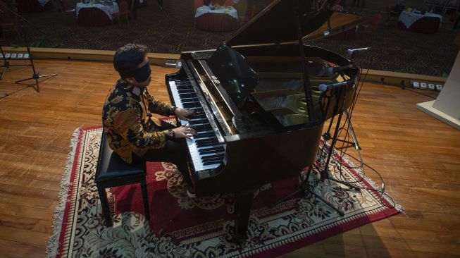 Pianis Jefri Setiawan (15) tampil dengan mata tertutup kain dalam konser pemecahan rekor di Universitas Yarsi, Jakarta, Rabu (24/3/2021). ANTARA FOTO/Aditya Pradana Putra