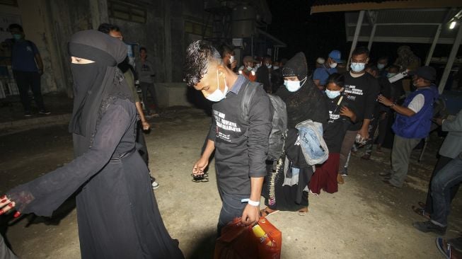 Pengungsi etnis Rohingya berjalan menuju bus saat akan diberangkatkan dari tempat penampungan Balai Latihan Kerja (BLK) Desa Meunasah Mee Kandang, Muara Dua, Lhokseumawe, Aceh, Kamis (25/2/2021) malam. [ANTARA FOTO/Rahmad]