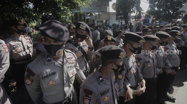 Petugas Kepolisian melakukan pengamanan saat berlangsungnya sidang lanjutan kasus pelanggaran protokol kesehatan dengan terdakwa Rizieq Shihab di depan Pengadilan Negeri (PN) Jakarta Timur, Jakarta, Jumat (26/3/2021). [Suara.com/Angga Budhiyanto]