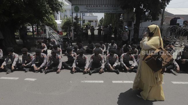 Petugas Kepolisian melakukan pengamanan saat berlangsungnya sidang lanjutan kasus pelanggaran protokol kesehatan dengan terdakwa Rizieq Shihab di depan Pengadilan Negeri (PN) Jakarta Timur, Jakarta, Jumat (26/3/2021). [Suara.com/Angga Budhiyanto]