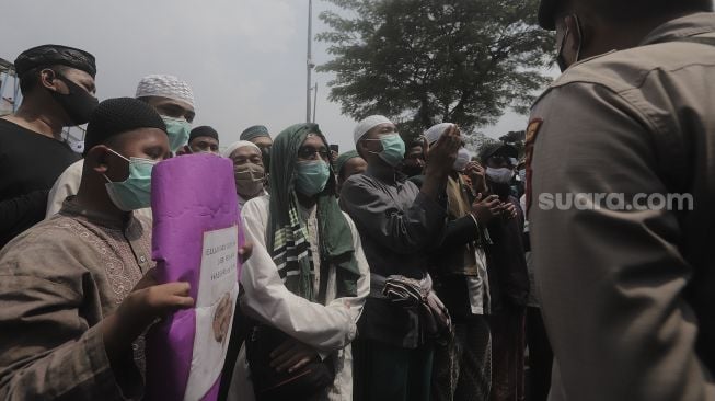 Massa pendukung Rizieq Shihab melakukan demonstrasi saat berlangsungnya sidang lanjutan kasus pelanggaran protokol kesehatan dengan terdakwa Rizieq Shihab di depan Pengadilan Negeri (PN) Jakarta Timur, Jakarta, Jumat (26/3/2021). [Suara.com/Angga Budhiyanto]