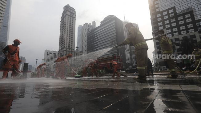 Petugas gabungan Unit Kerja Perangkat Daerah (UKPD) membersihkan trotoar sepanjang Jalan Sudirman-Thamrin, Jakarta, Sabtu (27/3/2021). [Suara.com/Angga Budhiyanto]