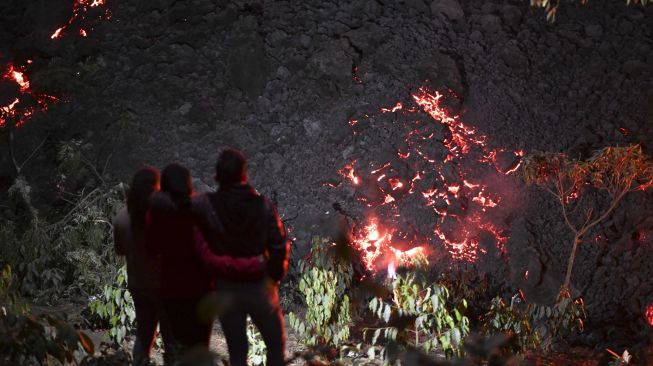 Orang-orang melihat aliran lava dari Gunung Berapi Pacaya Guatemala di pertanian La Brena di desa Patrocinio, San Vicente Pacaya, sekitar 60 kilometer selatan kota Guatemala, pada (25/3/2021). [Johan ORDONEZ / AFP]