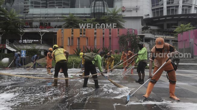 Petugas gabungan Unit Kerja Perangkat Daerah (UKPD) membersihkan trotoar sepanjang Jalan Sudirman-Thamrin, Jakarta, Sabtu (27/3/2021). [Suara.com/Angga Budhiyanto]