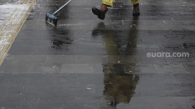 Petugas gabungan Unit Kerja Perangkat Daerah (UKPD) membersihkan trotoar sepanjang Jalan Sudirman-Thamrin, Jakarta, Sabtu (27/3/2021). [Suara.com/Angga Budhiyanto]