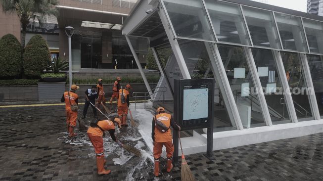 Petugas gabungan Unit Kerja Perangkat Daerah (UKPD) membersihkan trotoar sepanjang Jalan Sudirman-Thamrin, Jakarta, Sabtu (27/3/2021). [Suara.com/Angga Budhiyanto]