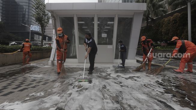 Petugas gabungan Unit Kerja Perangkat Daerah (UKPD) membersihkan trotoar sepanjang Jalan Sudirman-Thamrin, Jakarta, Sabtu (27/3/2021). [Suara.com/Angga Budhiyanto]