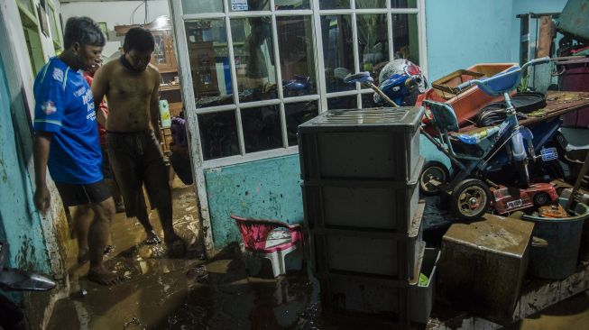 Warga membersihkan rumah dari sisa lumpur pascabanjir luapan sungai di Sukamiskin, Bandung, Jawa Barat, Sabtu (27/3/2021).  ANTARA FOTO/Novrian Arbi
