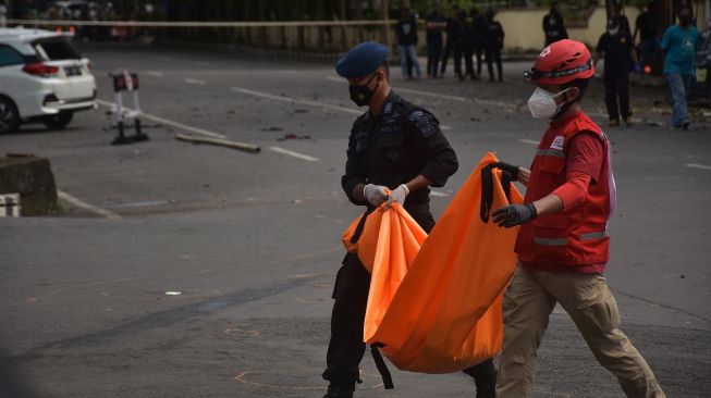 Petugas kepolisian mengangkat kantong jenazah berisi bagian tubuh dari terduga pelaku bom bunuh diri di depan Gereja Katedral Makassar, Sulawesi Selatan, Minggu (28/3/2021).  ANTARA FOTO/Indra Abriyanto