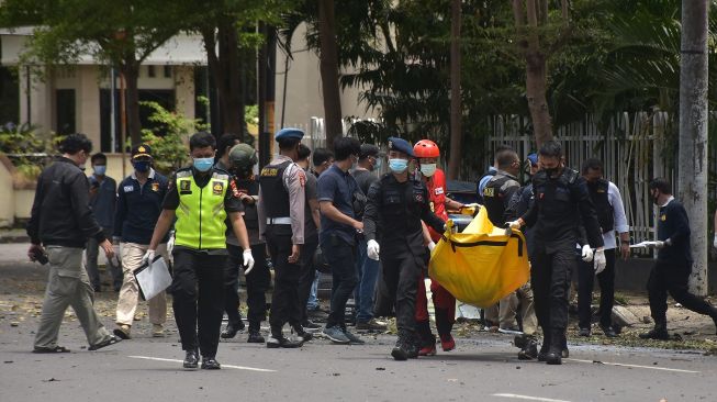 Petugas kepolisian mengangkat kantong jenazah berisi bagian tubuh dari terduga pelaku bom bunuh diri di depan Gereja Katedral Makassar, Sulawesi Selatan, Minggu (28/3/2021).  ANTARA FOTO/Indra Abriyanto