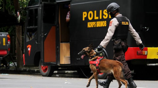 Anggota polisi berjalan dengan anjing pelacak saat mengumpulkan sisa serpihan ledakan bom bunuh diri di depan Gereja Katedral Makassar, Sulawesi Selatan, Senin (29/3/2021). ANTARA FOTO/Arnas Padda