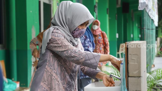 Orang Tua murid  mencuci tangan saat melaksanakan simulasi sekolah tatap muka Hybrid di SMP Negeri 255, Jakarta Timur, Selasa (30/3/2021). [Suara.com/Alfian Winanto]