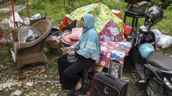 Warga duduk di dekat perabot miliknya usai penertiban bangunan di kawasan Menteng Dalam, Tebet, Jakarta Selatan, Selasa (30/3/2021). ANTARA FOTO/M Risyal Hidayat