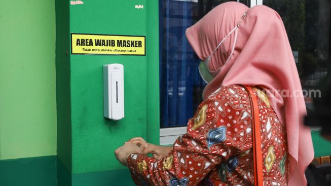 Orang Tua mencuci tangan dengan handsinitizer saat melaksanakan simulasi sekolah tatap muka Hybrid di SMP Negeri 255, Jakarta Timur, Selasa (30/3/2021). [Suara.com/Alfian Winanto]