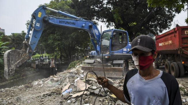 Warga mengangkat sisa bangunan miliknya yang telah ditertibkan di kawasan Menteng Dalam, Tebet, Jakarta Selatan, Selasa (30/3/2021).  ANTARA FOTO/M Risyal Hidayat
