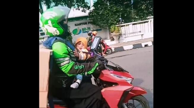 Ojol kerja keras angkut barang besar sambil gendong anak (Facebook)