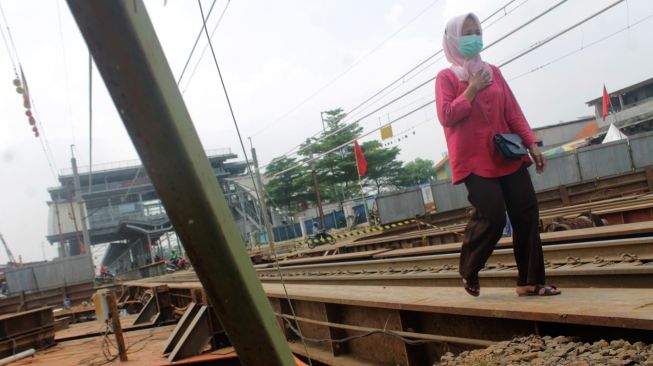 Pejalan kaki melewati jembatan rel kereta, Kecamatan Cibitung, Kabupaten Bekasi, Rabu (31/03/21). [Suara.com/Dian Latifah]