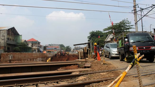 Pengendara melewati jalur perlintasan kereta api yang berada di samping proyek Underpass Cibitung, Kecamatan Cibitung, Kabupaten Bekasi, Rabu (31/03/21). [Suara.com/Dian Latifah]