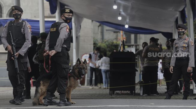 Personel kepolisian berjaga di depan Gereja Katedral, Jakarta, Kamis (1/4/2021). [Suara.com/Angga Budhiyanto]