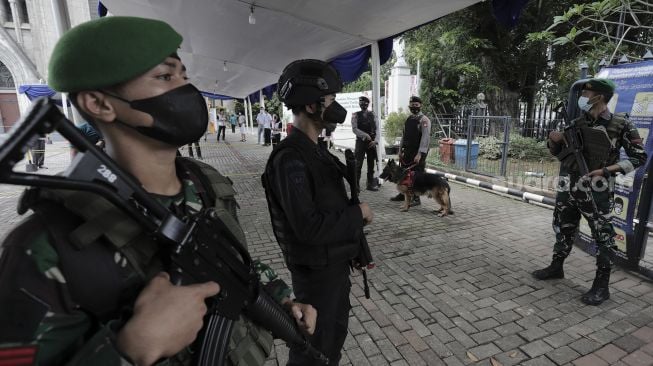 Personel gabungan berjaga di depan Gereja Katedral, Jakarta, Kamis (1/4/2021). [Suara.com/Angga Budhiyanto]