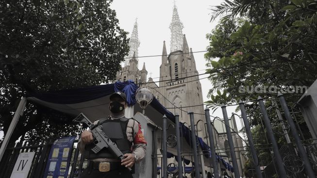 Personel kepolisian berjaga di depan Gereja Katedral, Jakarta, Kamis (1/4/2021). [Suara.com/Angga Budhiyanto]