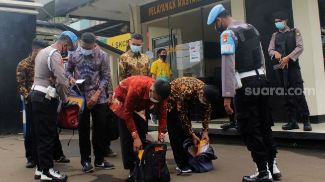 Petugas kepolisian memeriksa barang bawaan pendaftar anggota polri di Polres Metro Bekasi Kota, Kota Bekasi, Kamis (01/04/21). [Suara.com/Dian Latifah] 