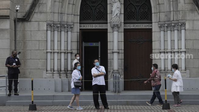 Jemaat berjalan memasuki Gereja Katedral, Jakarta, Kamis (1/4/2021). [Suara.com/Angga Budhiyanto]