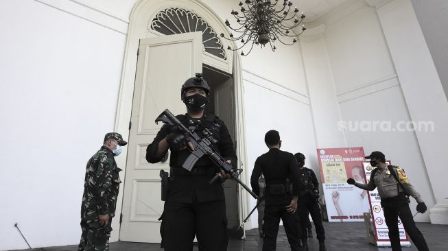 Petugas kepolisian berjaga saat melakukan pengamanan dan sterilisasi di sela berlangsungnya misa Jumat Agung menjelang hari raya Paskah di Gereja Immanuel, Jakarta, Jumat (2/4/2021). [Suara.com/Angga Budhiyanto]