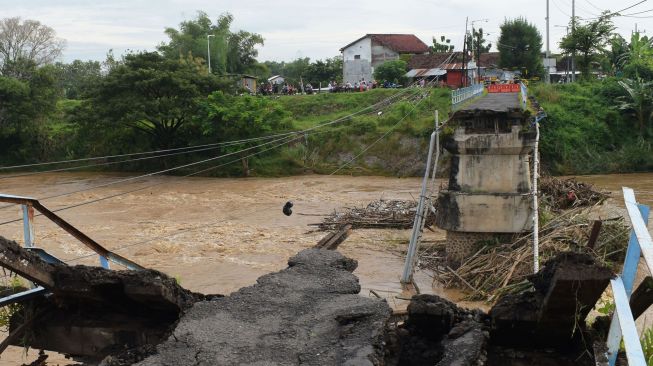 Warga melihat kondisi jembatan yang putus di Sungai Madiun, Kota Madiun, Jawa Timur, Jumat (2/4/2021).  ANTARA FOTO/Siswowidodo