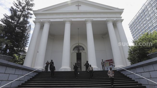 Petugas kepolisian berjaga saat melakukan pengamanan dan sterilisasi di sela berlangsungnya misa Jumat Agung menjelang hari raya Paskah di Gereja Immanuel, Jakarta, Jumat (2/4/2021). [Suara.com/Angga Budhiyanto]