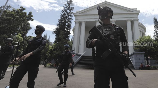 Petugas kepolisian berjaga saat melakukan pengamanan dan sterilisasi di sela berlangsungnya misa Jumat Agung menjelang hari raya Paskah di Gereja Immanuel, Jakarta, Jumat (2/4/2021). [Suara.com/Angga Budhiyanto]