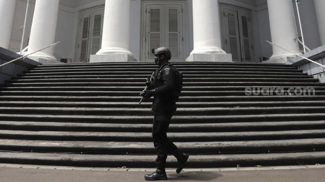 Petugas kepolisian berjaga saat melakukan pengamanan dan sterilisasi di sela berlangsungnya misa Jumat Agung menjelang hari raya Paskah di Gereja Immanuel, Jakarta, Jumat (2/4/2021). [Suara.com/Angga Budhiyanto]