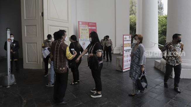 Petugas memeriksa suhu tubuh jemaat yang akan mengikuti ibadah misa Jumat Agung rangkaian hari raya Paskah di Gereja Immanuel, Jakarta, Jumat (2/4/2021). [Suara.com/Angga Budhiyanto]